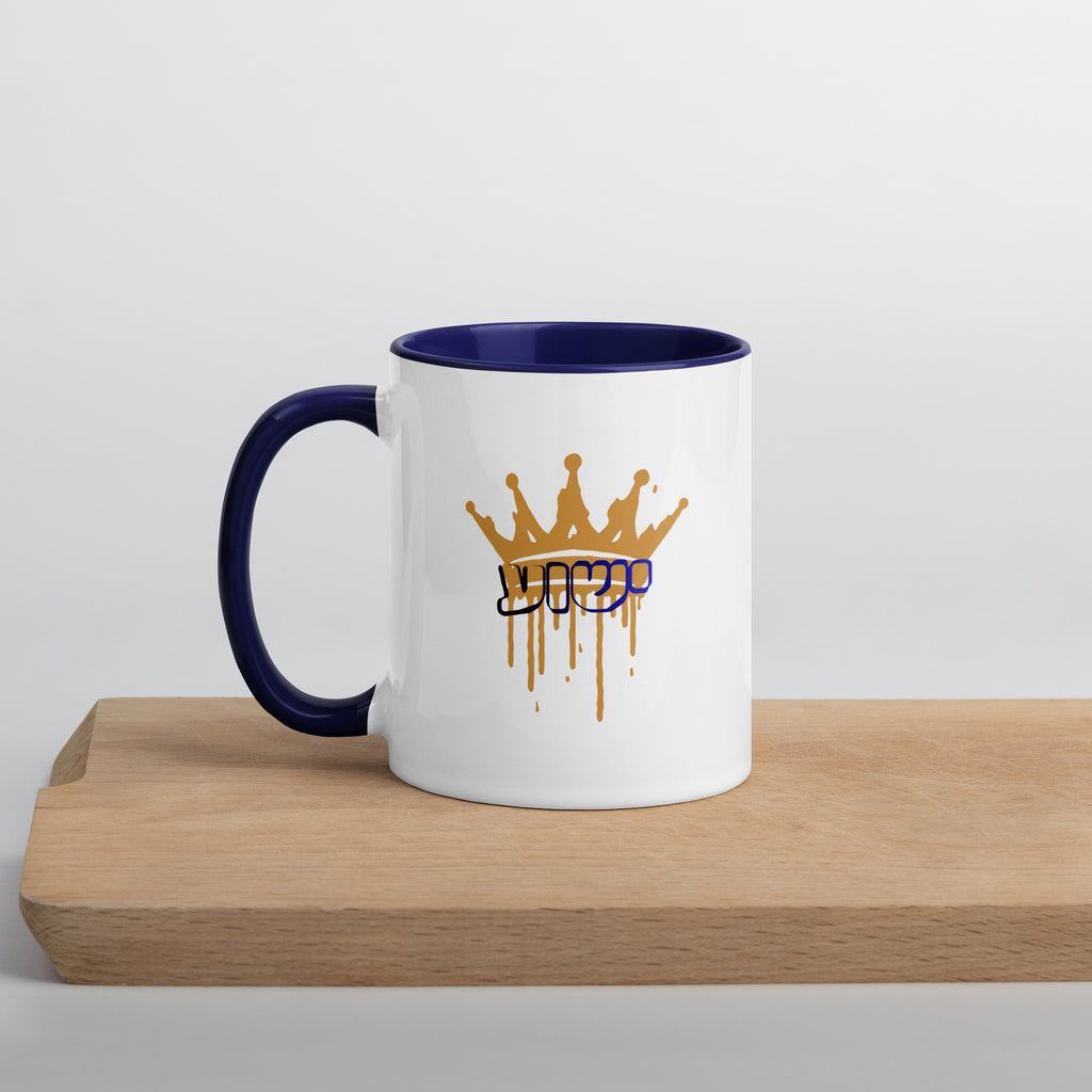 11 oz | Front view of white and blue Yeshua King ceramic coffee mug on a wooden board, featuring ישוע in Hebrew beneath a dripping gold crown with blue handle, rim, and interior.